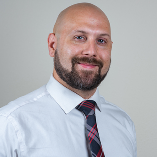 Portrait of Dr. Chris Maxson, a licensed chiropractor, smiling confidently in a professional setting, representing expertise and dedication to patient wellness and spinal health.